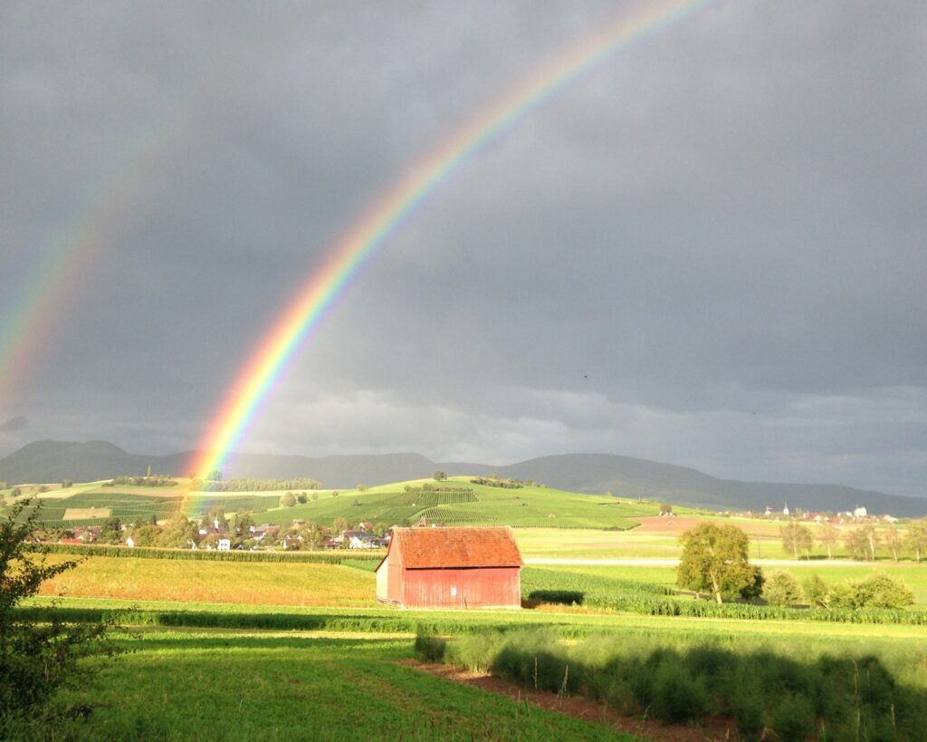 photo of double rainbow over fields and farmhouse