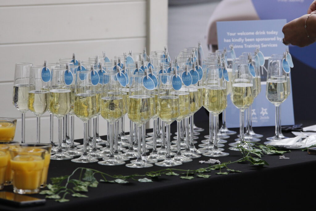 champagne glasses lined up on table with quinns business logo pegged onto them