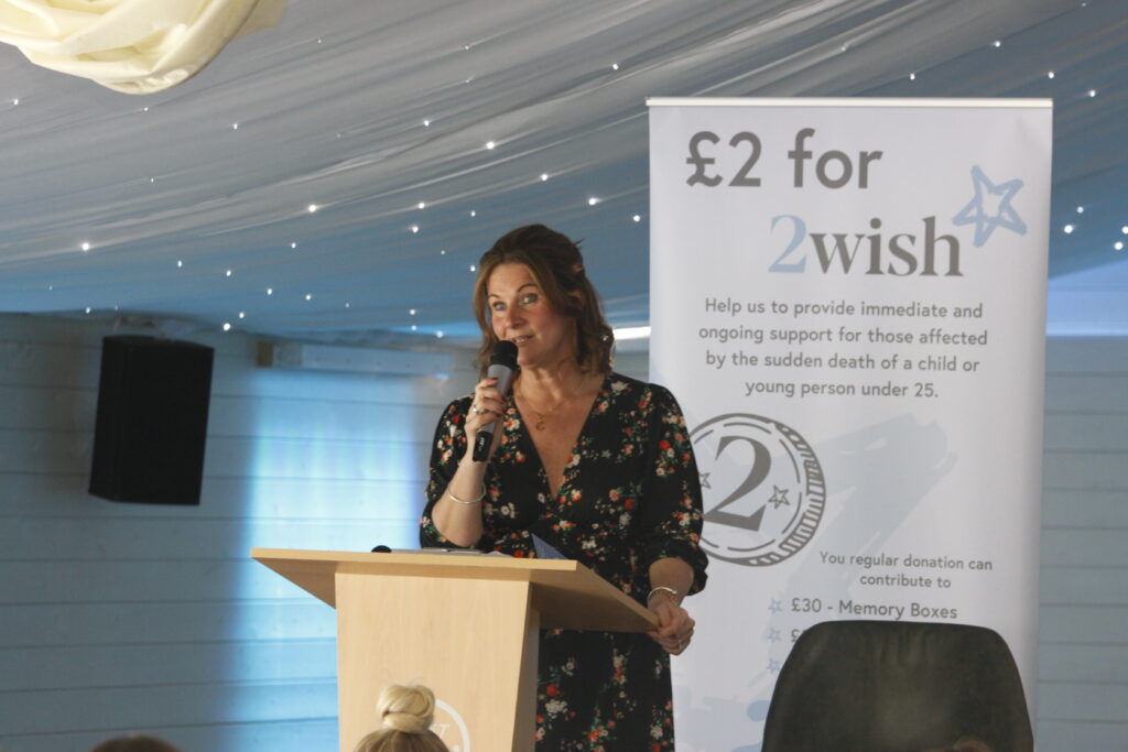rhian mannings ceo and founder of 2wish standing behind podium speaking with microphone in hand